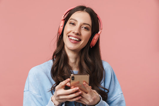 Image of delighted woman laughing while using headphones and cellphone