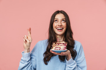 Image of attractive young woman making wish while holding birthday cake