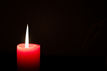 One light candle burning brightly with flower vase in the black background