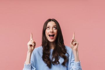 Image of young woman smiling and pointing fingers at empty space