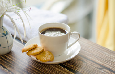 Cup of hot coffee with .butter cookies and flower on a wooden table holiday home vacation ideas