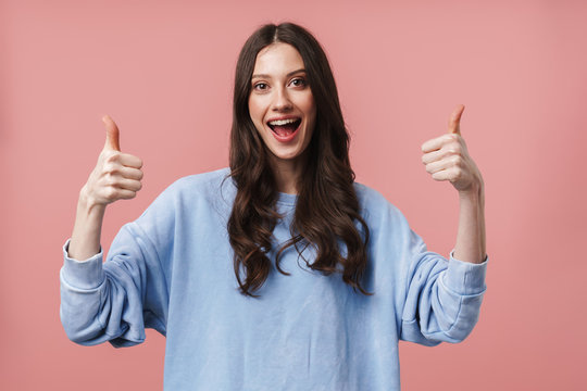 Image of attractive young woman smiling and gesturing thumbs up