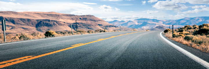 Long road through desert, empty street leading into the mountains, two lanes asphalt route