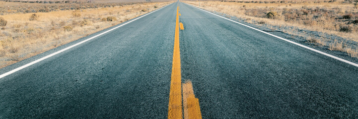 Long straight road through desert, empty street leading into horizon, two lanes asphalt route