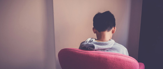 Sad preteen boy sitting alone in chair facing wall, depressed,introvert,  autism awareness,...