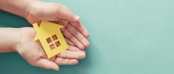 Foto op Canvas hands holding paper house, family home, homeless housing and home protecting insurance concept, international day of families, foster home care, homeschooling, social distancing © SewcreamStudio