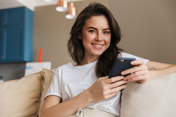 Beautiful young brunette woman relaxing on a couch at home