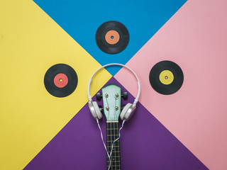 Vinyl discs, guitar and headphones on a multicolored background.