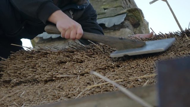 A Man Thatching A Roof Using A Leggett To Dress Up The Thatched.-  closeup shot