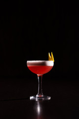 pink cocktail on a neutral black background with white foam