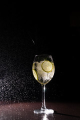 refreshing cocktail on a neutral black background with flying splashes in the air
