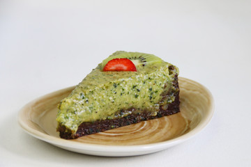 raw basil cheesecake with lime and mint close up on plate and light background. vegan dessert concept