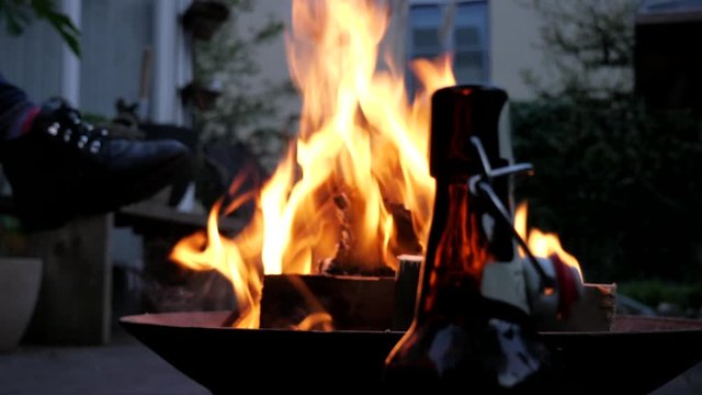 Bottle of beer with romantic fire in background outdoor, close up