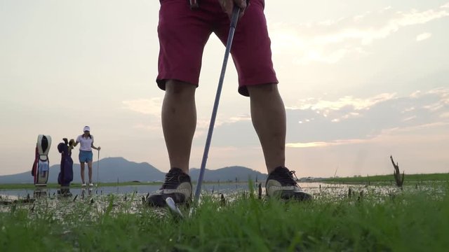 Footage B Roll Of Slow Motion Couple Lover In Action Of Playing Golf Together. Golf Ball Away From The Rough To Fairway, Difficult Time Stay Together In The Family Course. Beautiful Nature Silhouette.