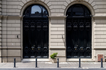 Two black entrance doors with bronze knobs in a classic style building