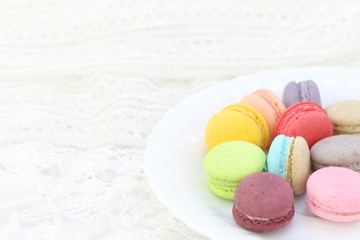 Close up colorful fresh sweet cake macarons in white dish on white fabric background, have copy space for put text.