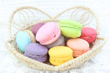 Obraz na płótnie Canvas Closeup colorful macaron pile in wooden basket on white fabric background
