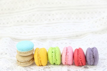 Close up colorful fresh sweet cake macarons stack horizontal line on white fabric background, have copy space for put text.