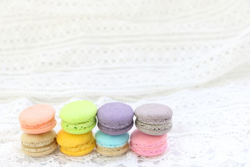 Close up colorful fresh sweet cake macarons stack horizontal line on white fabric background, have copy space for put text.