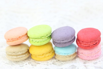 Close up colorful fresh sweet cake macarons stack horizontal line on white fabric background, have copy space for put text.