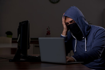 Male hacker hacking security firewall late in office