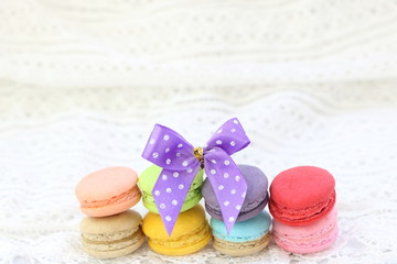 Close up colorful fresh sweet cake macarons stack horizontal line on white fabric background, have copy space for put text.