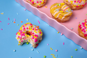 Sprinkled mini donuts on a pink serving tray on a colorful background