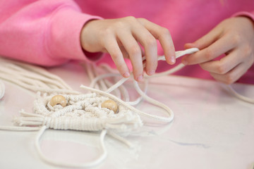 Children's hands weave from a cord, a macrame weaving master class