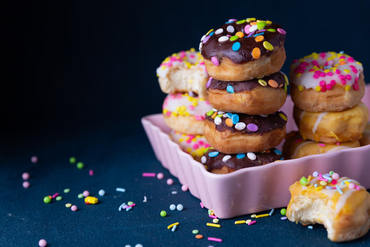 Sprinkled mini donuts stacked with a dark background