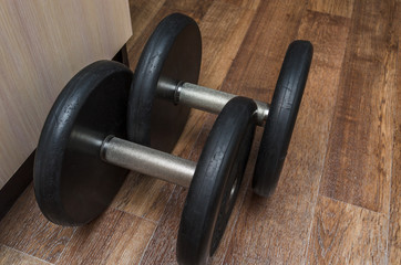 sports dumbbells on the floor in the apartment. We sit at home and play sports.