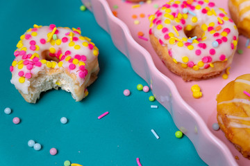 Sprinkled mini donuts on a pink serving tray on a colorful background