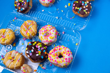 Messy sprinkled mini donuts in a clam shell package on blue