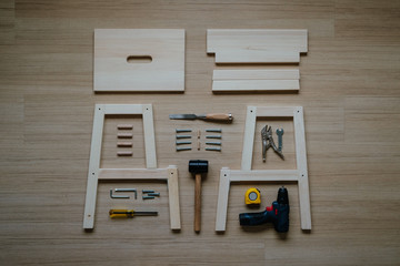 Top view of furniture assembly parts and wood work tools on wooden floor for DIY do it yourself