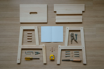 Top view of furniture assembly parts and tools on wooden floor for DIY do it yourself and assemble the work, blank space instruction paper to put logo