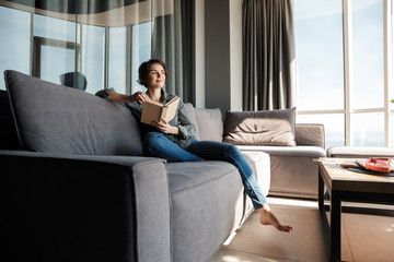Image of brunette cute pleased woman reading book and smiling