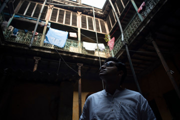 Naklejka na ściany i meble An young Indian Bengali detective with traditional wear looking upward inside an old vintage house in the morning. Indian lifestyle.