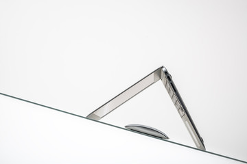 computer mouse under inverted laptop on inclined glass table surface isolated on white background  