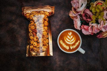 Close up top view cups of cappuccino with latte art and caramel popcorn on wooden background.