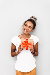 Positive optimistic happy young african woman with dreads isolated over white wall background holding present gift box.