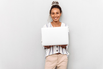 Happy positive young african business woman with dreads isolated over white wall background using laptop computer.