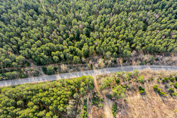 Fototapeta na wymiar top down aerial view of road going through green forest landscape