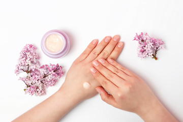 Women's hands smear cream on white background, a view from above