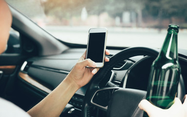 Asian men drink alcohol in the car and using mobile phones while driving.