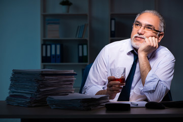 Old male employee working late in the office