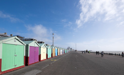 Fototapeta premium People exercising on Hove seafront near Brighton, UK, with colourful beach huts
