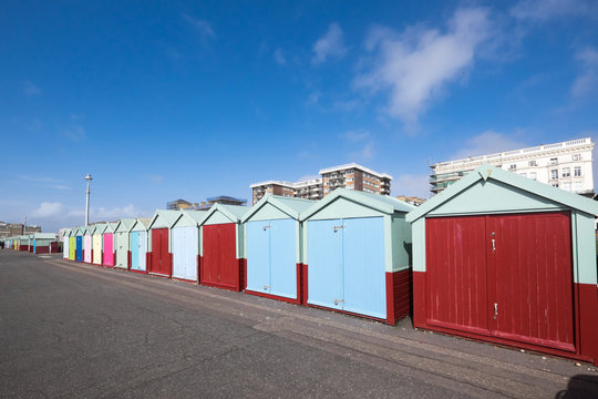 Beach huts on Hove seafront in Brighton, Sussex, UK, with apartment block buildings with blue sky