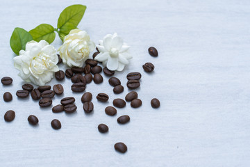 Jasmine flower and roasted coffee bean on textured tile plate.