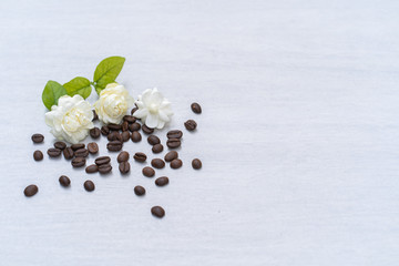 Jasmine flower and roasted coffee bean on textured tile plate.
