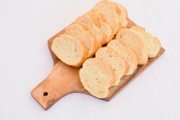 Fresh sliced french bread on a wooden cutting board isolated on white, fresh baked, delivery option, restaurant website menu, take out food, fresh loaf on a cutting board 