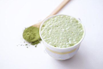 matcha latte in a cup and matcha powder in wooden spoon. healthy drinks concept. modern fashionable drink for weight loss and energy boost. top view
